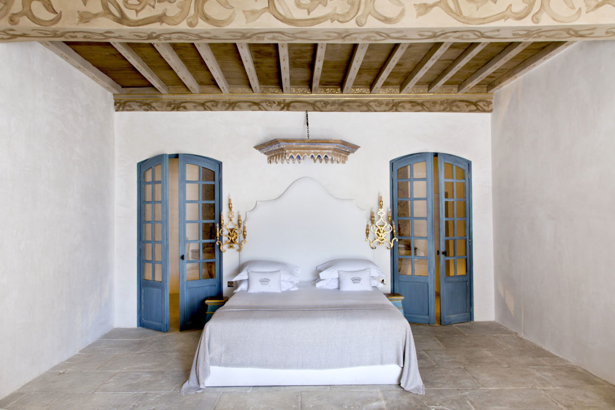 Chambre avec ciel de lit d'antiquaire et appliques façon candélabres.
